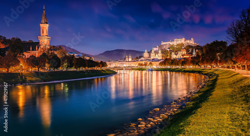 Beautiful view of Festung Hohensalzburg and Castle Hohensalzburg during sunset with colorful sky with reflection in Salzach river in evening, Salzburg, Austria. Popular travel and historical center