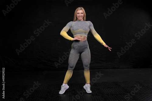 well-built girl with blond hair posing confidently showing her sportiness. fitness clothing
