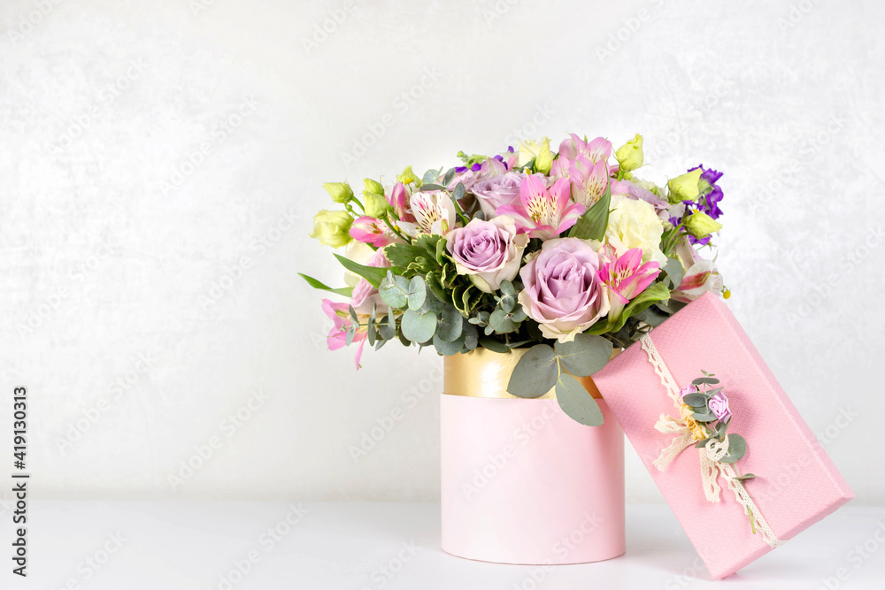 Beautiful bouquet of flowers in round box and pink gift box on a white table. Gift for holiday, birthday, Wedding, Mother's Day, Valentine's day, Women's Day. Floral arrangement in a hat box.