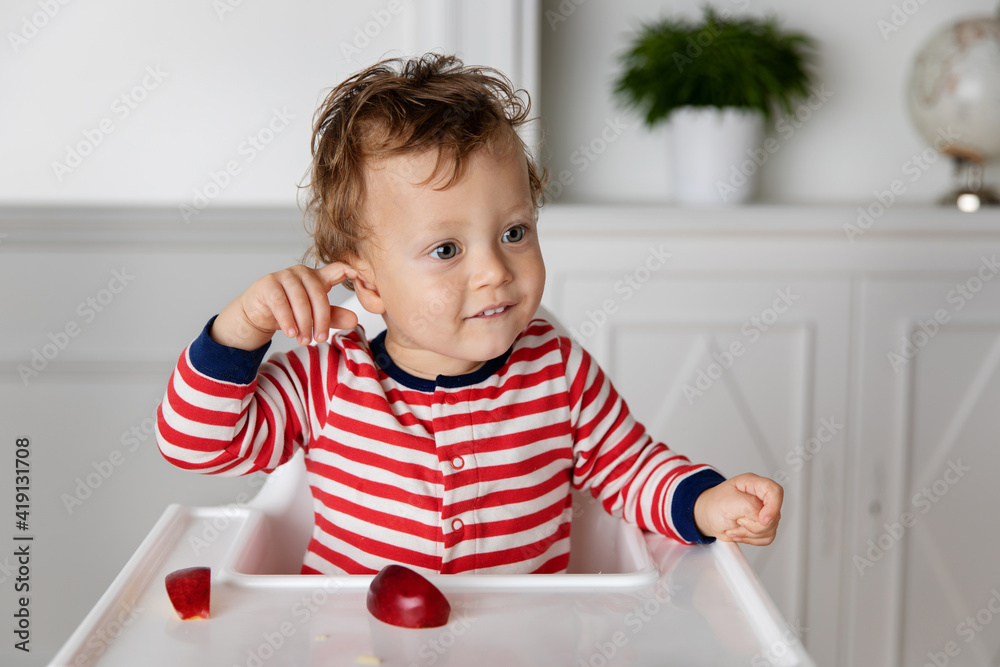Baby in high chair touching his ear with his finger Baby in high chair touching his ear with his finger