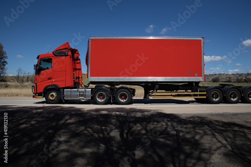 Truck on a freeway in an Australian Country Town midway between Sydney and Melbourne with nice blue sky and lush green trees as a backdrop