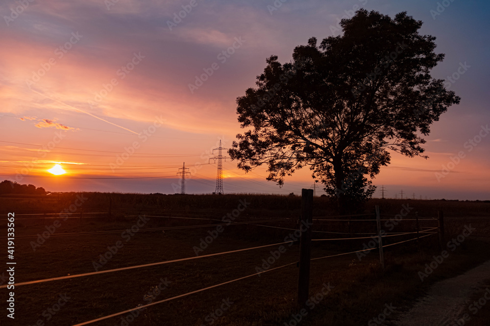 Beautiful sunset with a dramatic sky and overland high voltage lines near Tabertshausen, Bavaria, Germany Beautiful sunset with a dramatic sky and overland high voltage lines near Tabertshausen, Bavaria, Germany