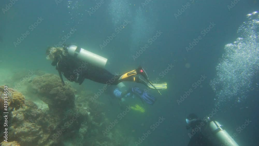 Scuba Divers swim over coral reef with fishes in blue sea. Tropical colorful underwater seascape with coral reef. Camiguin, Philippines. Scuba Divers swim over coral reef with fishes in blue sea. Tropical colorful underwater seascape with coral reef. Camiguin, Philippines.
