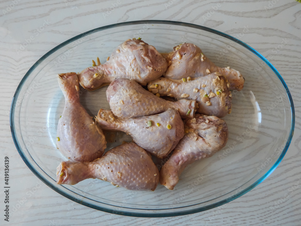 chicken legs marinated with garlic in a glass bowl
