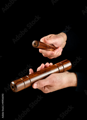 Fotografie hands playing cuban clave on black background