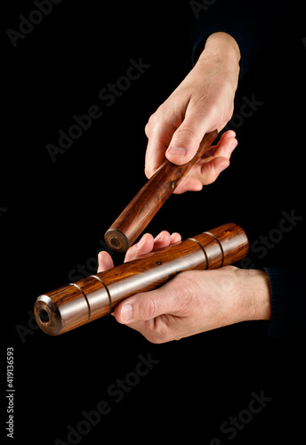 hands playing cuban clave on black background