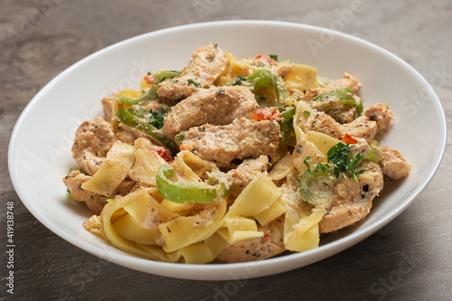 Close Up cajun chicken Fettuccine pasta in a creamy sauce on white plate ready to eat. Creole cuisine.