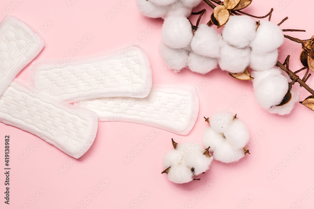 Women's hygiene daily pads on pink background and cotton sprigs, banner Women's hygiene daily pads on pink background and cotton sprigs, banner