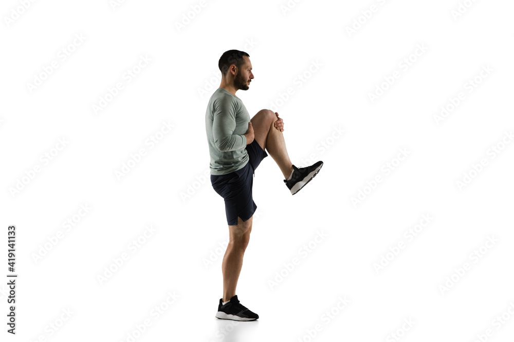 Stretching. Young caucasian male model in action, motion isolated on white background with copyspace. Concept of sport, movement, energy and dynamic, healthy lifestyle. Training, practicing. Authentic