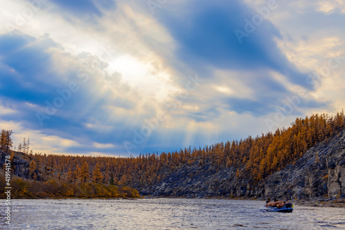 Heavenly landscape with sun rays over the autumn taiga river.