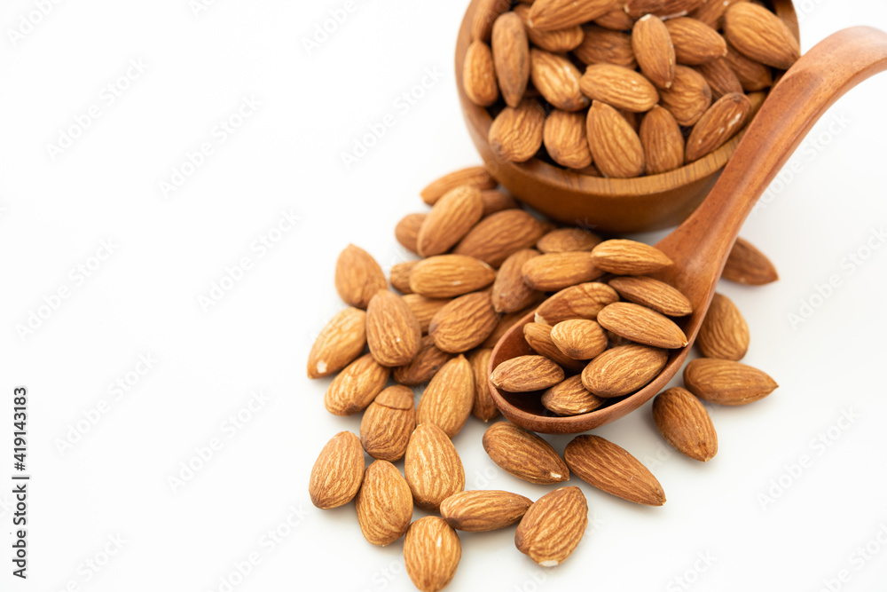 almond in a wooden spoon and bowl on white background. (selective focus; close-up shot) almond in a wooden spoon and bowl on white background. (selective focus; close-up shot)