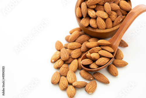 almond in a wooden spoon and bowl on white background. (selective focus; close-up shot)