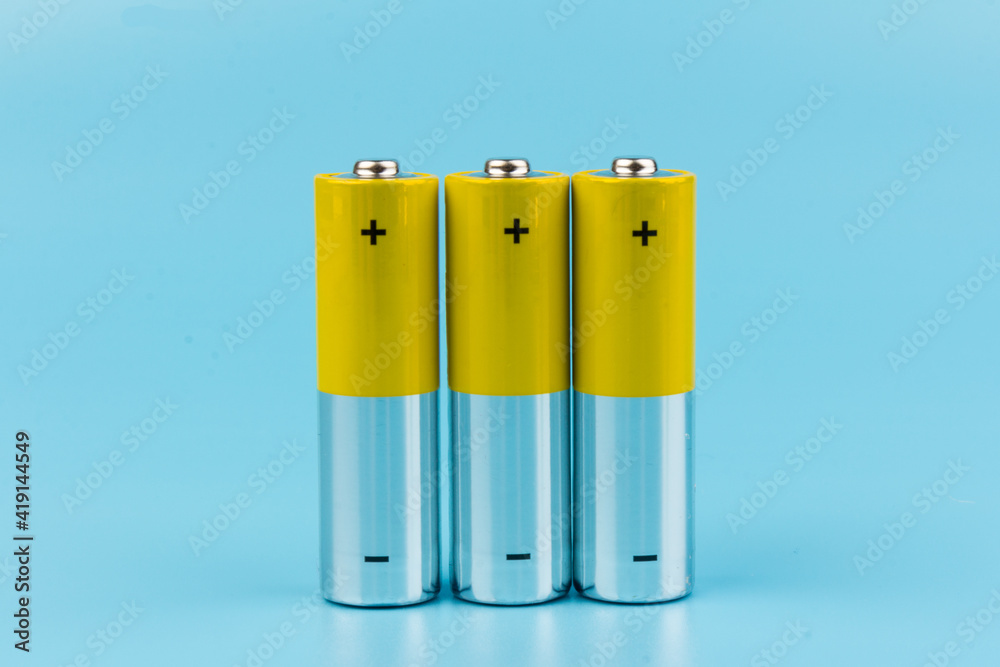 Photo of gray-yellow alkaline AA batteries on blue background. Recycling of rechargeable NiMH batteries. The most popular size of accumulators. Copy space. Photo of gray-yellow alkaline AA batteries on blue background. Recycling of rechargeable NiMH batteries. The most popular size of accumulators. Copy space.