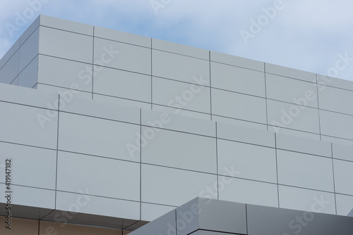 The exterior wall of a contemporary commercial style building with aluminum metal composite panels and glass windows. The futuristic building has engineered diagonal cladding steel frame panels. 