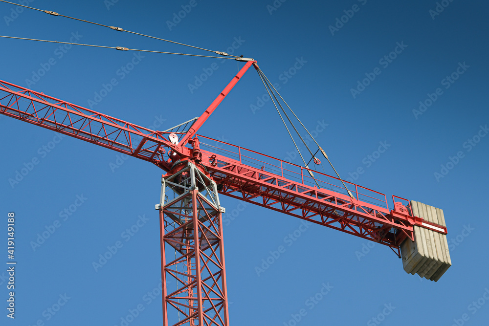 Industrial landscape. Red crane on a construction site with blue sky background. Industrial landscape. Red crane on a construction site with blue sky background.