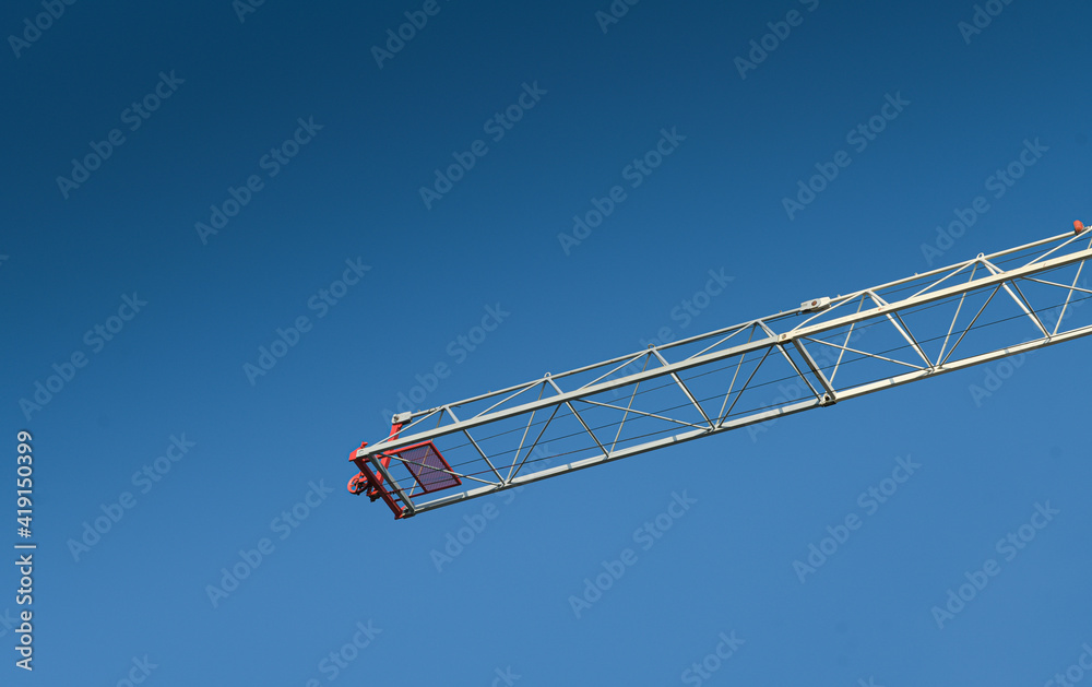 Industrial landscape. Red crane on a construction site with blue sky background. Industrial landscape. Red crane on a construction site with blue sky background.