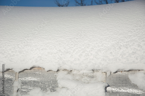 Snow lies on the roof of the greenhouse. Film greenhouse under the snow in the garden. Winter in the garden.