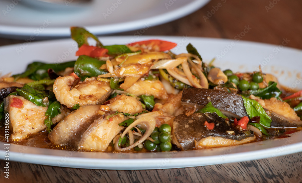 hot and spicy stir fried fresh fish with herb in thai style. Contains fresh pepper, chili, lemongrass, lime leaf