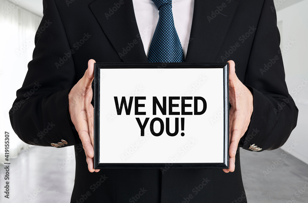 Businessman holds a signboard with the message we need you. Human resources recruitment or employment Businessman holds a signboard with the message we need you. Human resources recruitment or employment
