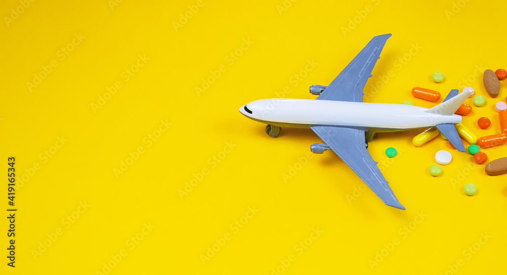 model airplane with multicolored pills from motion sickness close-up on a yellow background. concept illness in travel.selective focus model airplane with multicolored pills from motion sickness close-up on a yellow background. concept illness in travel.selective focus