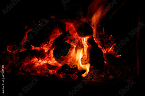 Incandescent charcoal ember in orange and yellow tones