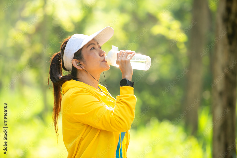 Healthy athletic woman drinking pure water after go running to be fresh in the nature park. Asian runner woman after exercise. Healthy and Lifestyle concept. On Nature background. Healthy athletic woman drinking pure water after go running to be fresh in the nature park. Asian runner woman after exercise. Healthy and Lifestyle concept. On Nature background.