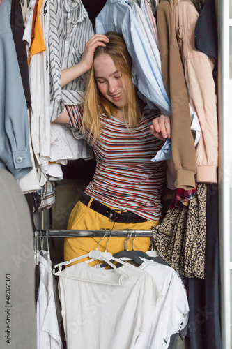 Spring cleaning,Fast fashion, the girl puts things in order in the closet. A bunch of colorful clothes. The concept of processing, second hand, eco, minimalism, consumption of goods