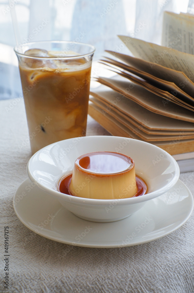 Soft focus Pudding Dessert caramel pudding in a white plate is placed on a white table by the window. Soft focus Pudding Dessert caramel pudding in a white plate is placed on a white table by the window.