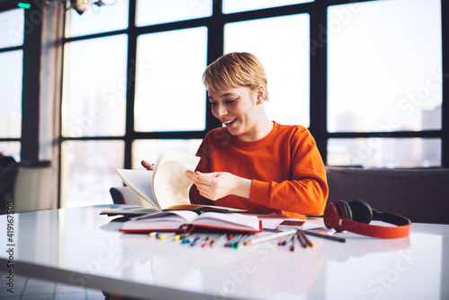 Photos Happy androgynous person flipping pages in workplace