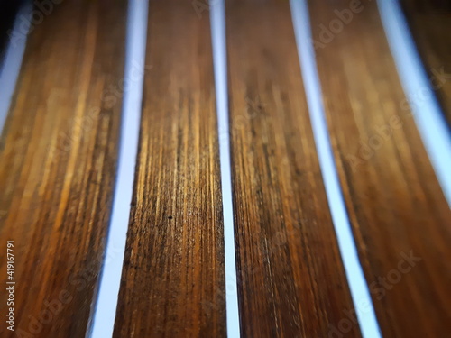 Abstract shot of wooden strips in macro and selective focus with yellow light on blue background.