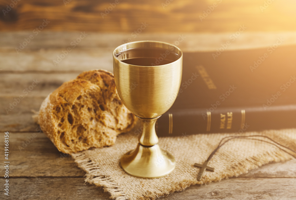 Chalice of wine with bread and Holy Bible on wooden background Stock