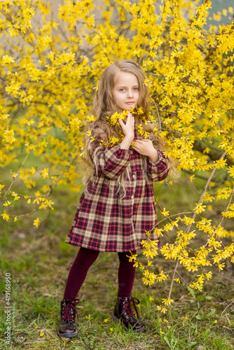 girl on a background of yellow flowers. A child in a blooming spring garden