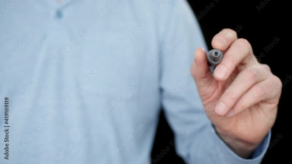 Male hand writing with marker on transparent board front camera. Left hand writing with marker on transparent board on black background Male hand writing with marker on transparent board front camera. Left hand writing with marker on transparent board on black background