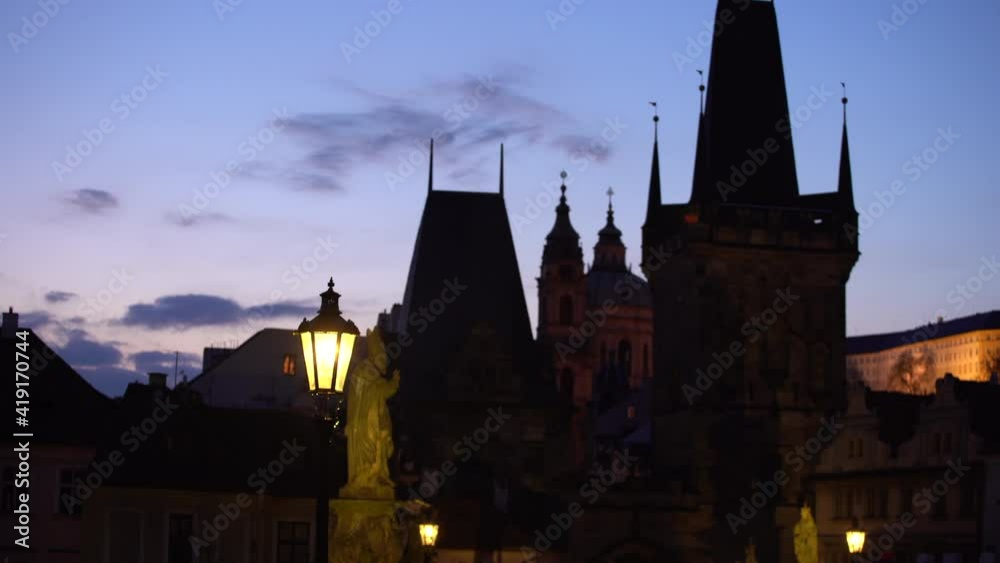 lanterns and silhouettes of the towers on Charles bridge and in the background the Prague Castle and the Cathedral of St. Vitus Bridge at dawn lanterns and silhouettes of the towers on Charles bridge and in the background the Prague Castle and the Cathedral of St. Vitus Bridge at dawn