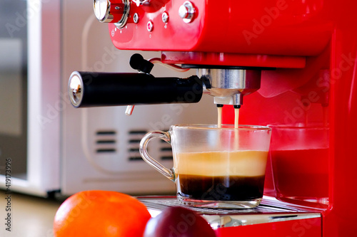 Two streams of espresso coffee on the espresso machine are poured into a transparent cup. Aromatic coffee with an appetizing foam.