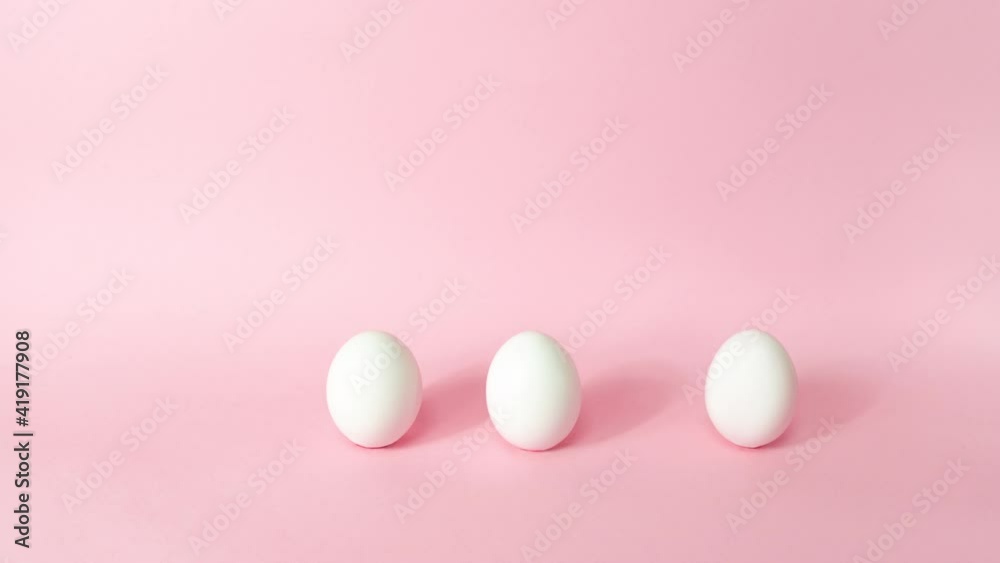 4k Three white chicken eggs dynamically emerge one at a time on light pink background. Happy Easter Day Concept. Greeting card. Stop motion animation. Copy space. 4k Three white chicken eggs dynamically emerge one at a time on light pink background. Happy Easter Day Concept. Greeting card. Stop motion animation. Copy space.