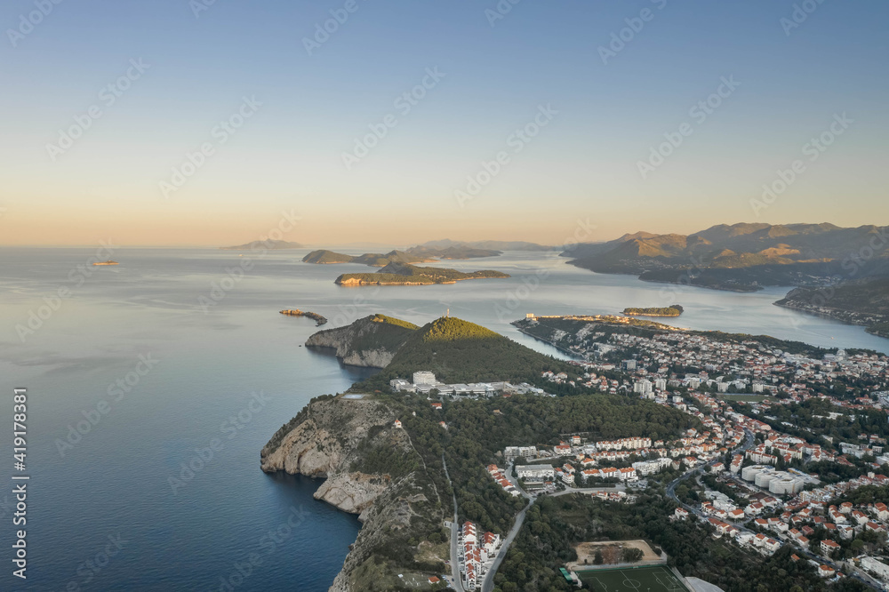 Aerial drone shot of Lapad hill in Dubrovnik town with sunrise over the peak in Croatia summer morning