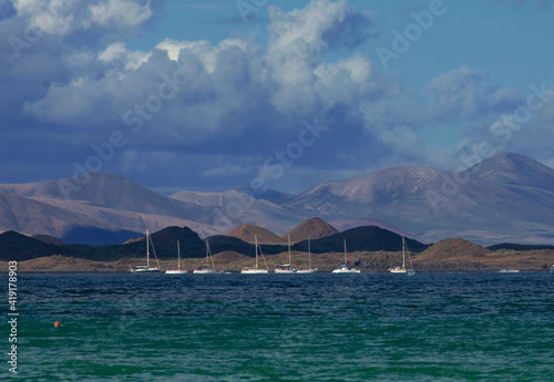 mountain range of the tropical island Fuerteventura with sailboats moored near the coast.Corralejo Canary Islands.