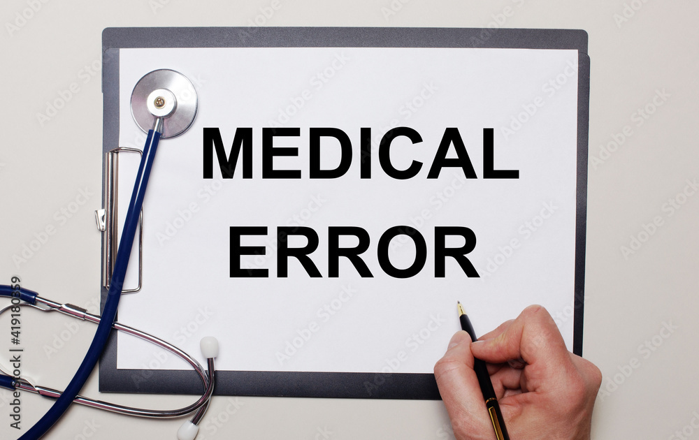 On a light background, a stethoscope and a sheet of paper, on which a man writes MEDICAL ERROR. Medical concept On a light background, a stethoscope and a sheet of paper, on which a man writes MEDICAL ERROR. Medical concept