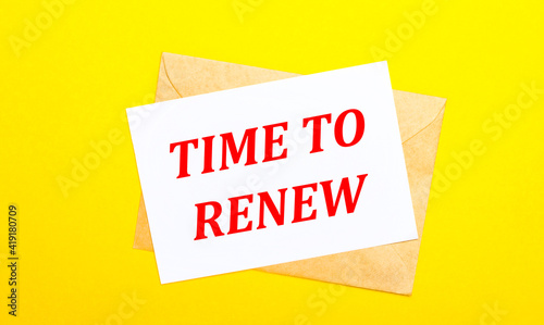 On a yellow background, an envelope and a card with the text TIME TO RENEW. View from above