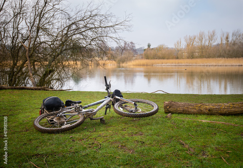 Bicycle on ground beside clear lake on winter's day near Chartham in Kent photo