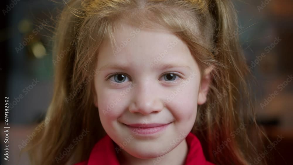 Portrait of happy young girl, smiling kid at home, European family, student in school class or in room, evening. Looking at camera Portrait of happy young girl, smiling kid at home, European family, student in school class or in room, evening. Looking at camera