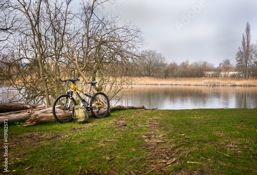 Bicycle and rug sack left beside lake on a bright winter day near Chartham in Kent.