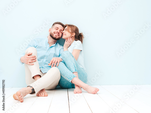 Smiling beautiful woman and her handsome boyfriend. Happy cheerful family having tender moments near light blue wall in studio.Pure cheerful models hugging.Embracing each other