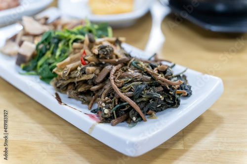 In Korean cuisine, side dishes such as seasoned vegetables are served on a white plate.
