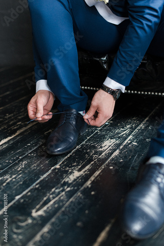 man ties the laces on black shoes close-up