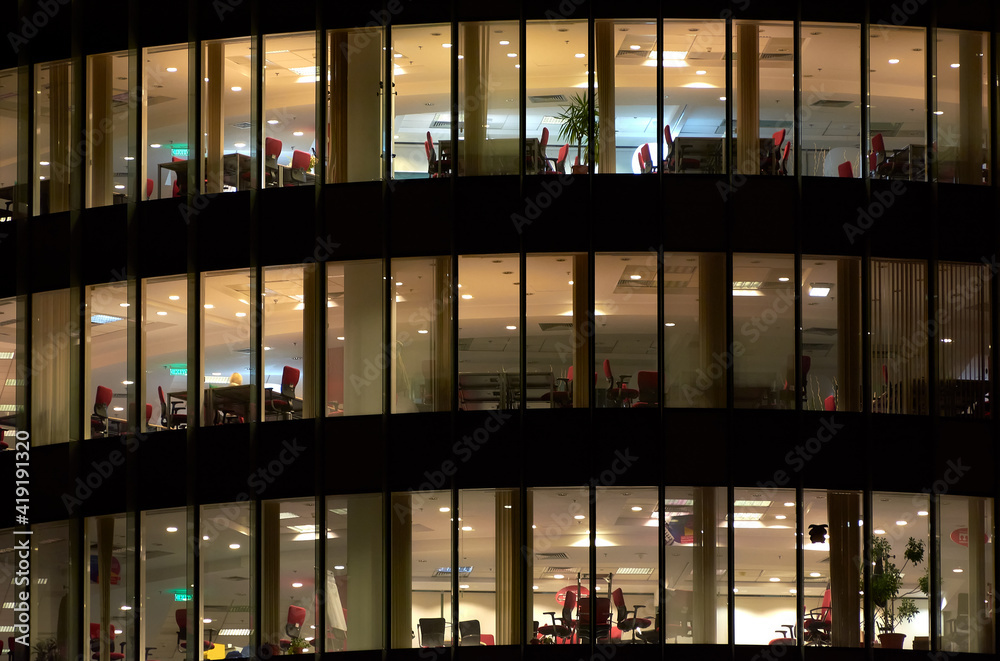 Multi-storey office building at night. Late night at office. Late night overtime in a modern office building Multi-storey office building at night. Late night at office. Late night overtime in a modern office building