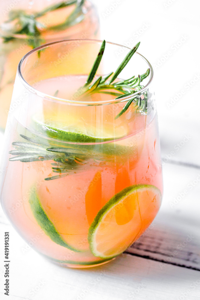 glass of fresh juice with lime and rosemary on white table background glass of fresh juice with lime and rosemary on white table background