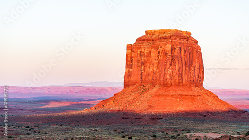 Panoramic view of famous Merrick butte mesa with vibrant red orange rock color on horizon in Monument Valley canyons during sunset in Arizona photo