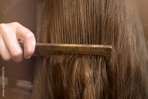 Comb your hair. Young woman combing her hair with long blond hair.